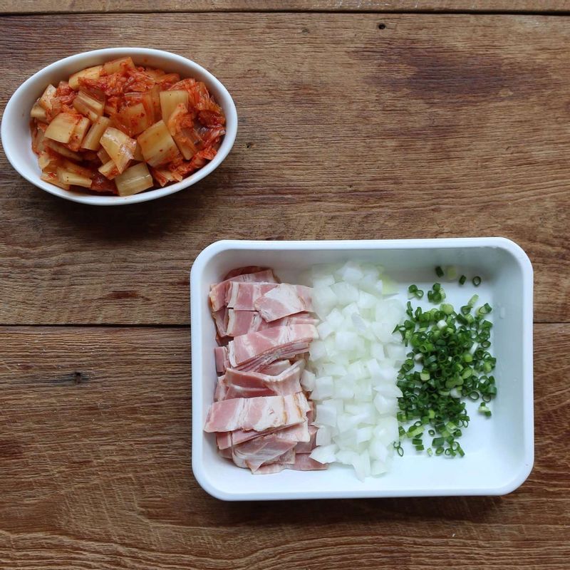 배추김치는 사방 1cm 크기로 자르고, 양파는 굵게 다져주세요. 실파는 송송 썰고, 베이컨은 한입 크기로 잘라주세요. 볼에 양념 재료를 넣어 섞어주세요.