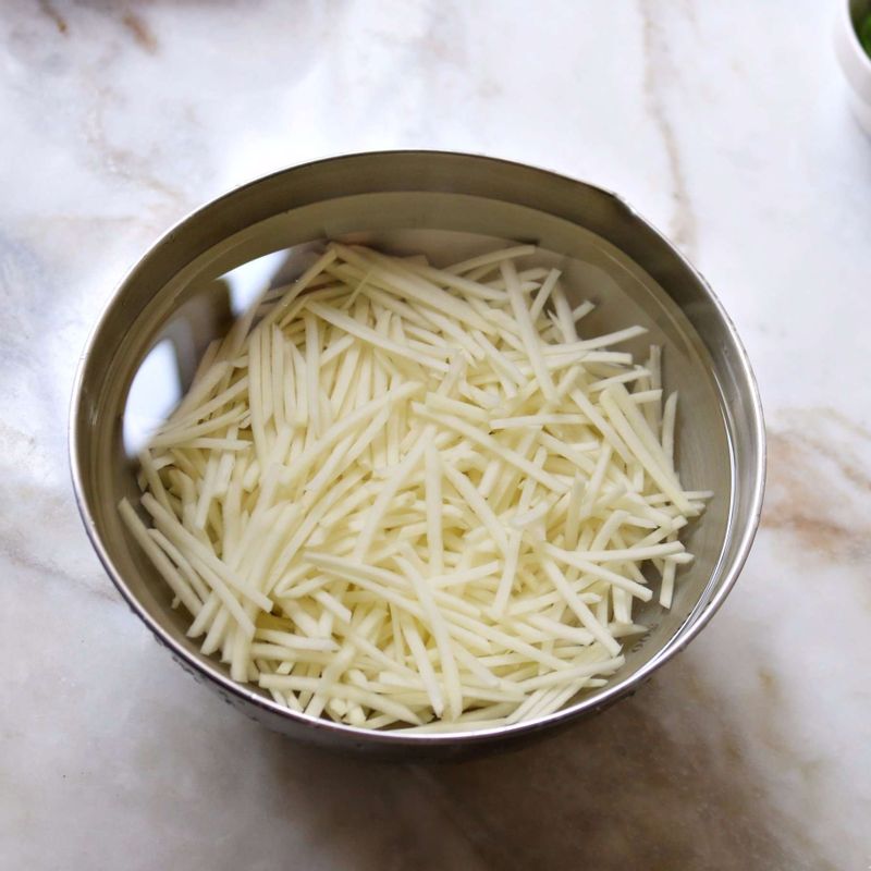 감자는 껍질을 벗기고 4센치 길이로 채 썬 후 찬물에 헹궈 전분을 빼고, 물에 5분 정도 담갔다가 체에 밭쳐 물기를 빼 주세요.