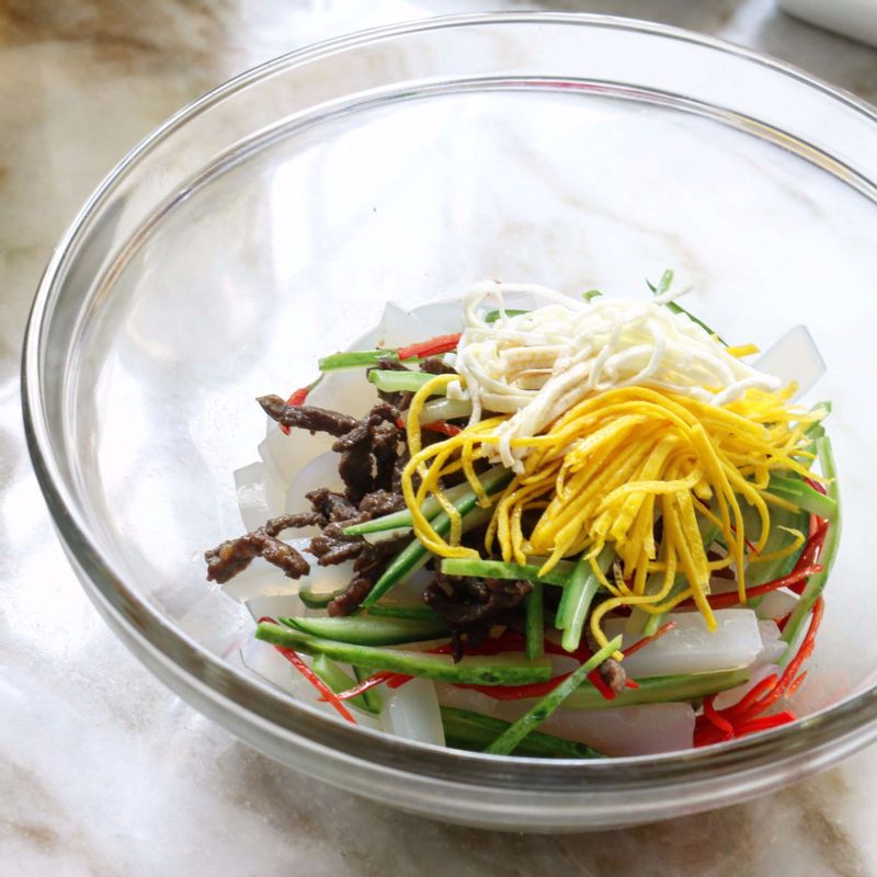 청포묵과 쇠고기, 지단채, 오이, 홍고추와 양념재료를 볼에 넣고 버무려주세요.