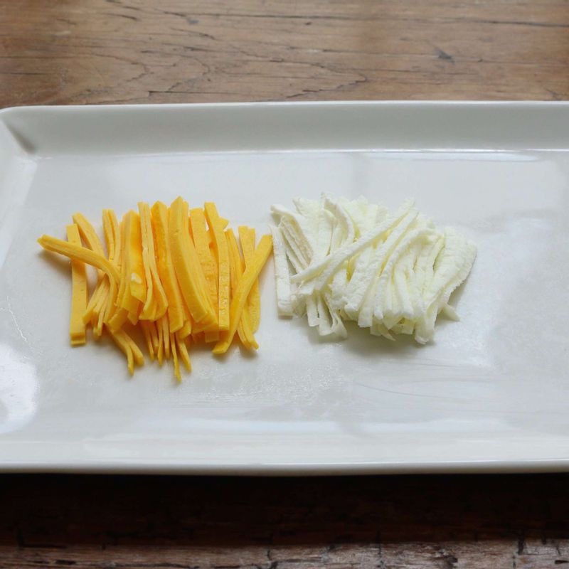 달걀은 노른자와 흰자를 나눈 후 약간의 소금을 넣고 고루 섞어 체에 내려주세요. 약한불에서 황백지단을 만들고 5센치 길이로 채를 썰어주세요.