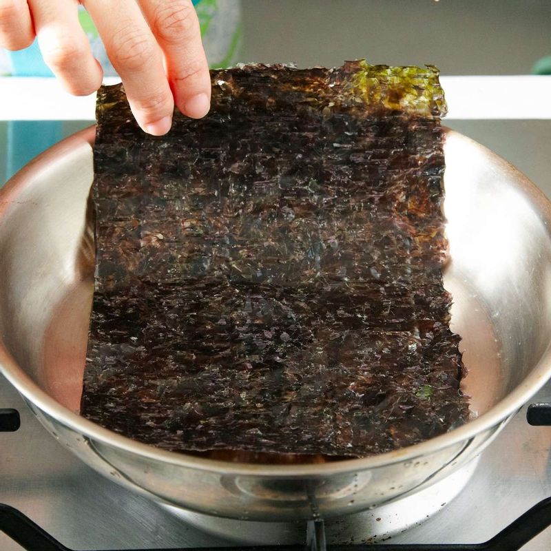 마른 팬에 김을 올려 앞뒤로 구운 뒤 비닐봉지에 넣어 곱게 부숴주세요.