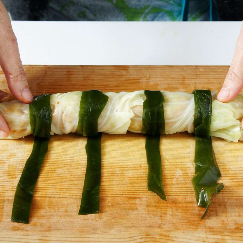 양배추말이밥을 일정한 간격을 두고 길게 썬 다시마로 묶어주세요.
다시마 사이사이를 썰어 마무리하세요.