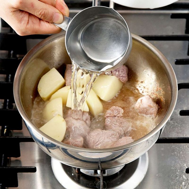 쇠고기 표면이 노릇하게 잘 구워지면 물을 붓고 채소 스톡 큐브를 넣어주세요.
뚜껑을 덮은 후 5분간 끓여주세요.