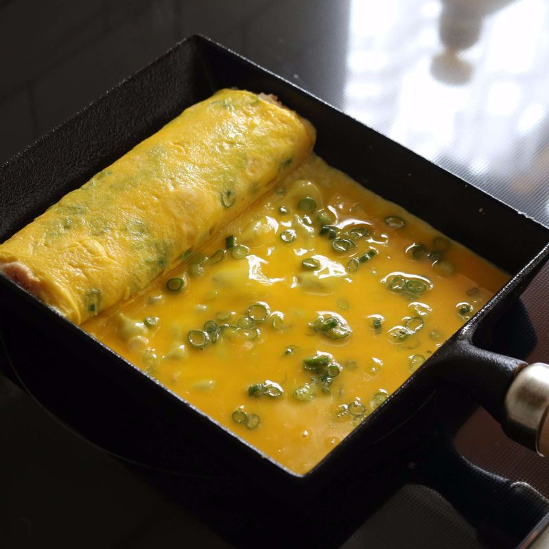 말아진 달걀을 팬 위쪽으로 밀어 놓고, 노른자를 다시 부어 2회 정도 같은 방법을 반복해서 말아주세요. 마지막에는 흰자를 붓고 같은 방법으로 말아주세요