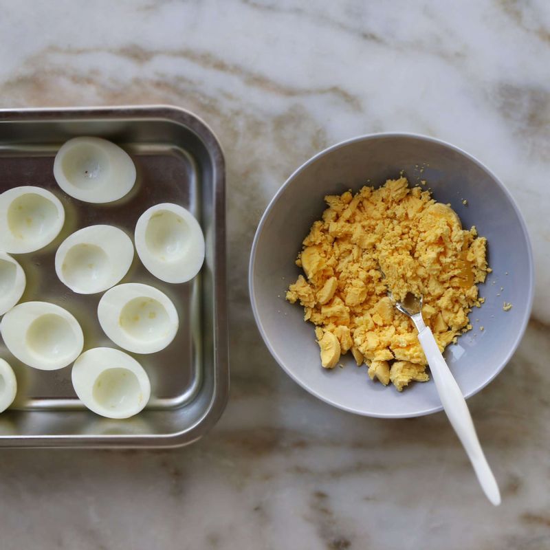 달걀을 가로로 반 자르고, 노른자는 빼내어 포크로 으깨주세요.