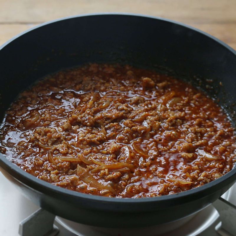 달군 팬에 고추기름을 두르고 양파, 돼지고기, 양념 재료를 넣어 3분 정도 볶아주세요.