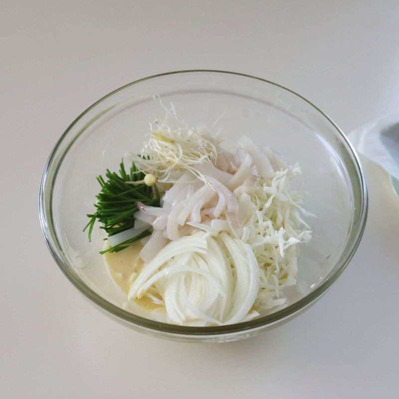 볼에 반죽 재료를 넣고 고루 섞은 후 양배추, 달래, 양파,오징어를 넣어 섞어주세요.