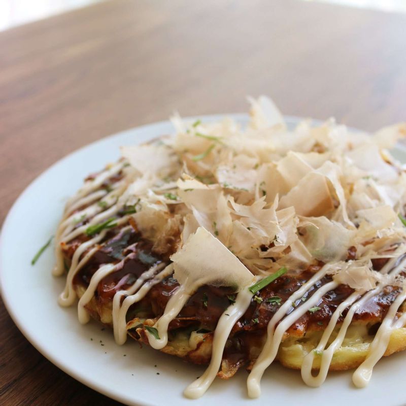 구운 오코노미야키에 돈가스 소스를 펴 바르고, 마요네즈를 뿌린 후 가쓰오부시와 송송 썬 달래를 올려주세요.