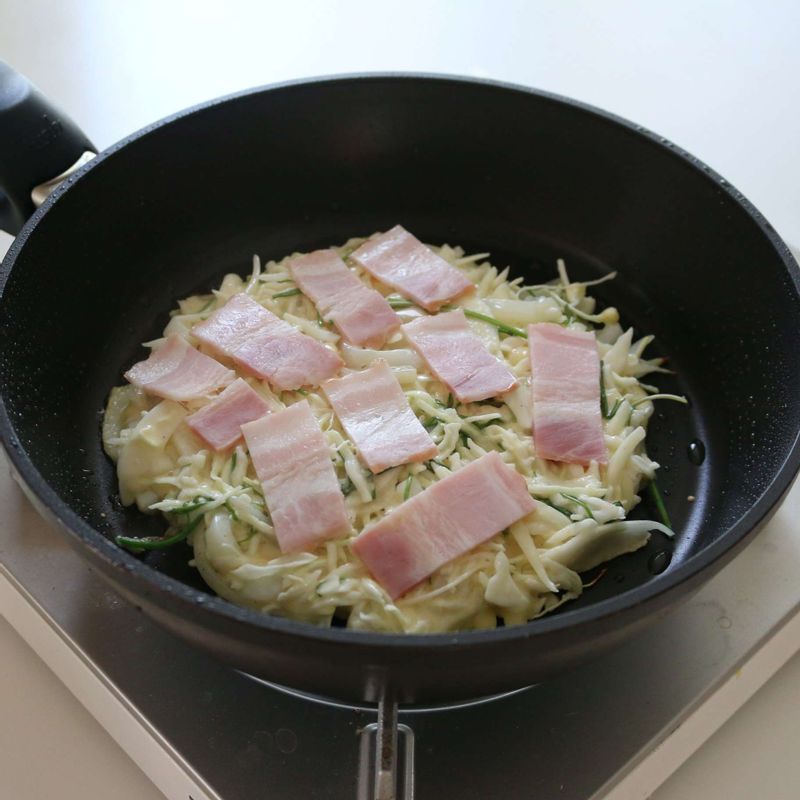 달군 팬에 기름을 두르고 반죽을 둥글게 펼친 후, 베이컨을 올리고 중간불에서 앞뒤로 노릇하게 구워주세요.