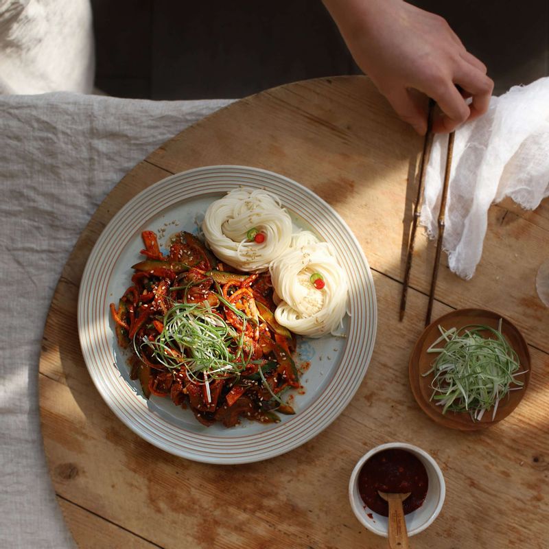 접시에 골뱅이무침을 담고 대파채를 올린 후, 삶은 소면을 함께 곁들이고 통깨를 뿌려주세요.