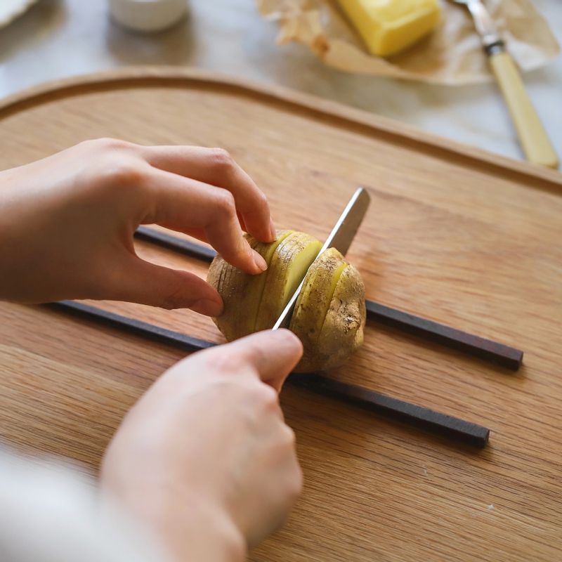 껍질째 깨끗이 씻은 감자는, 양쪽에 나무젓가락을 놓고 일정한 간격으로 얇게 칼집을 넣어주세요. 칼집을 넣은 감자를 찬물에 10분 정도 담가 전분기를 빼고 물기를 제거해주세요.