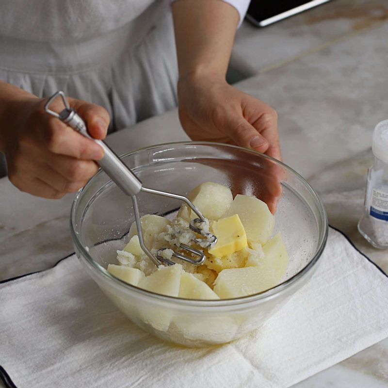 감자는 껍질을 벗겨 반으로 잘라 찜통에 넣어 30분 정도 쪄서 익히고, 뜨거울 때 으깬 후 버터와 소금, 후춧가루를 넣어 밑간해주세요.