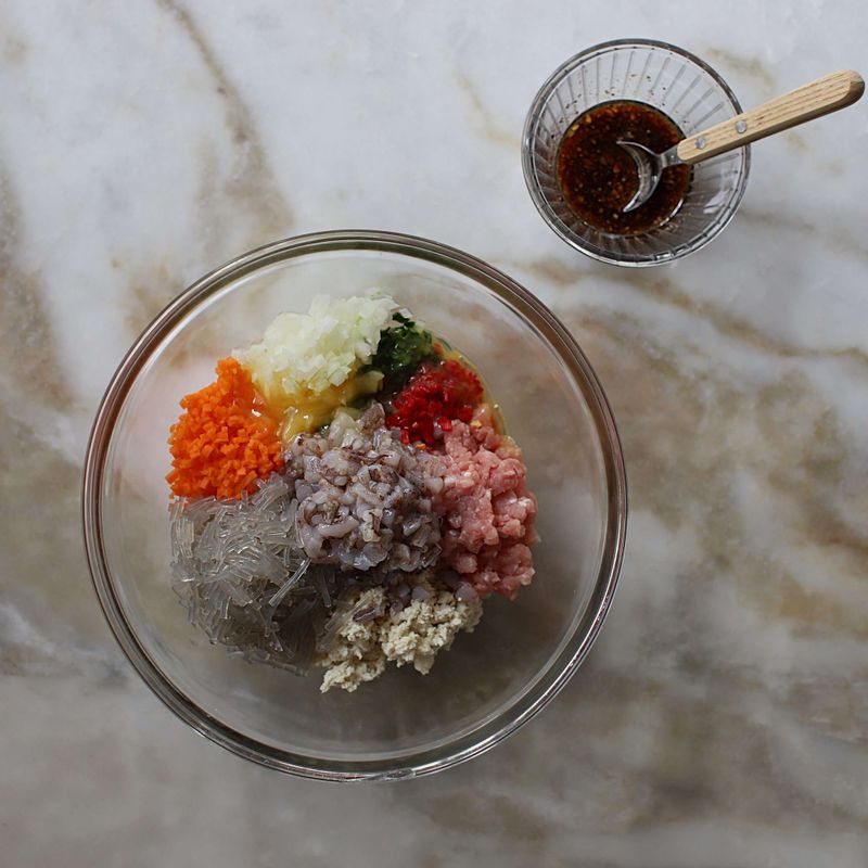 볼에 다진 돼지고기, 다진채소, 당면, 오징어 다리, 달걀물 1/2개분, 전분가루, 소 양념재료를 넣고 고루 섞으며 치대어 순대 소를 만들어주세요.