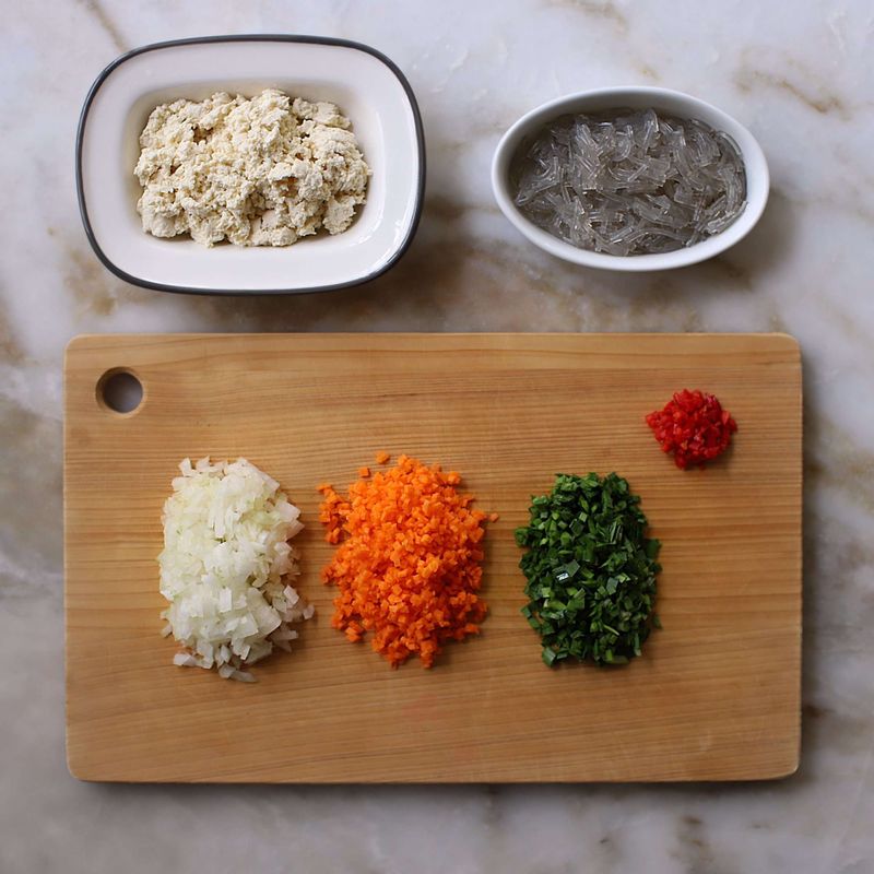 양파와 당근, 홍고추, 부추는 잘게 다져 물기를 제거하고 두부는 으깨어 면포에 넣어 물기를 짜주세요. 불린 당면은 끓는 물에 넣고 3분 정도 데친 후 잘게 다져주세요.