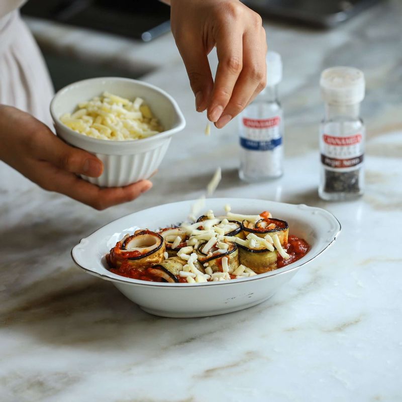 오븐 그라탕용기에 토마토소스를 깔고, 말아놓은 가지를 올린 후 소금과 후춧가루를 뿌려주세요. 모차렐라 피자치즈를 위에 뿌린 후 200도로 예열한 오븐에서 15-20분 구워주세요.