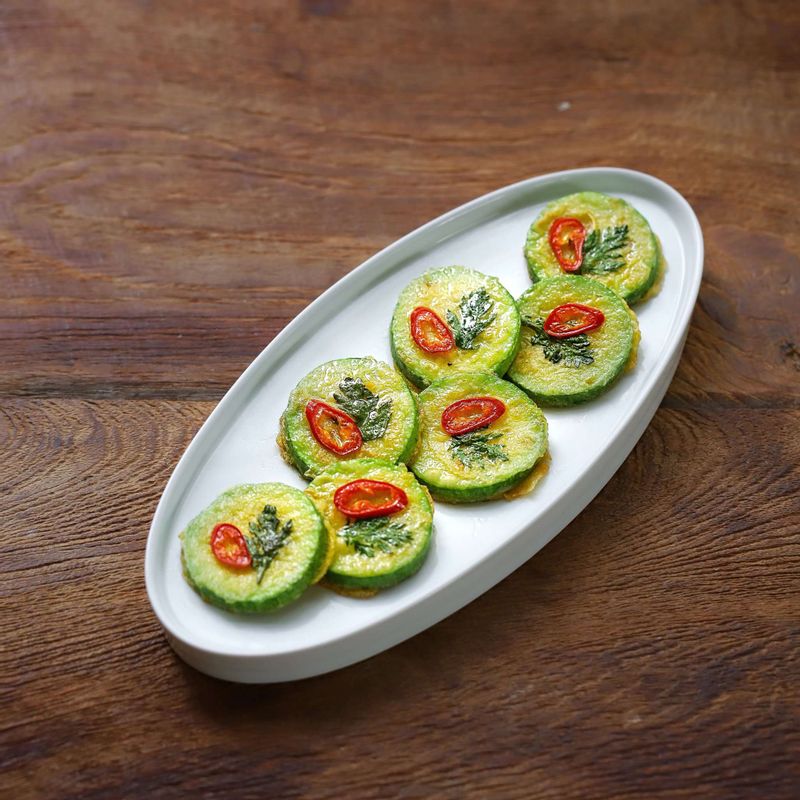 1. 애호박은 깨끗이 씻어서 0.5cm두께로 썰어주세요. 홍고추는 어슷썰기 해주세요.
2. 썰어놓은 애호박에 소금을 골고루 뿌리고, 약 5분 후 애호박에 생긴 물기를 닦아주세요.
3. 애호박에 부침가루를 묻히고 풀어놓은 달걀물에 담갔다가 건져주세요.
4. 달군팬에 약간의 기름을 두르고 애호박을 올린 후, 썰어 둔 홍고추와 쑥갓을 얹어 앞뒤로 약불에서 노릇하게 익혀주세요.