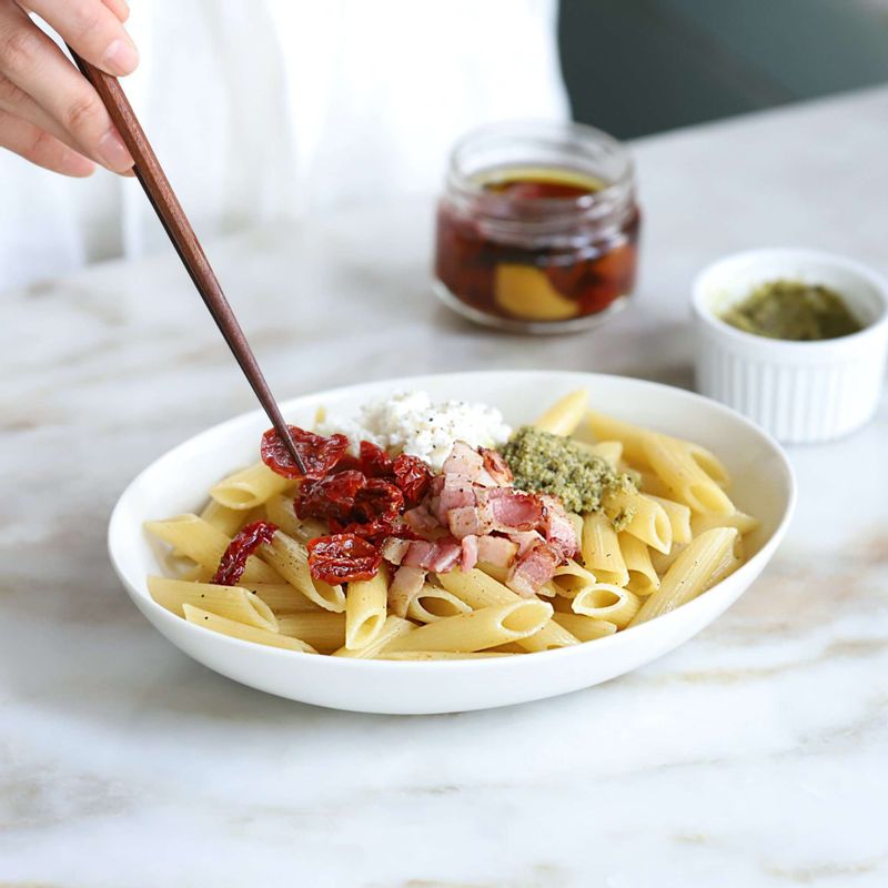 그릇에 완성된 파스타와 바질페스토, 선드라이드 토마토, 볶은 베이컨, 리코타치즈를 보기 좋게 올리고, 후춧가루를 뿌려 완성해주세요.