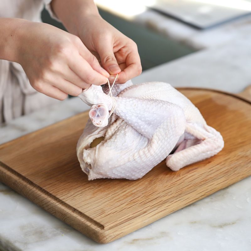 닭 속에 레몬과 로즈마리, 마늘을 넣어 조리용 실로 닭다리를 묶어주세요.