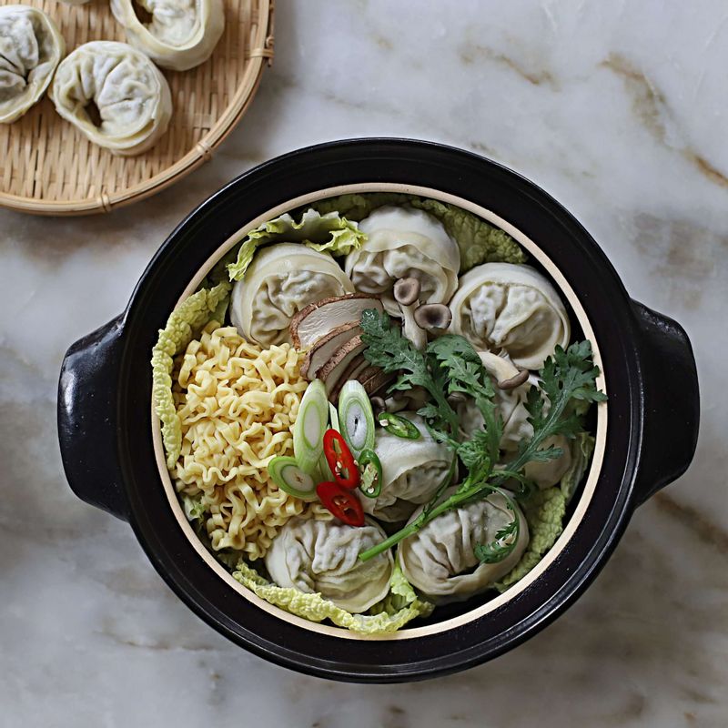 전골냄비 바닥에 배추를 깔고, 만두를 돌려담은 후 한쪽에는 삶아놓은 면을 넣어주세요. 가운데에 표고버섯,느타리버섯,대파,고추,쑥갓을 담아주세요.