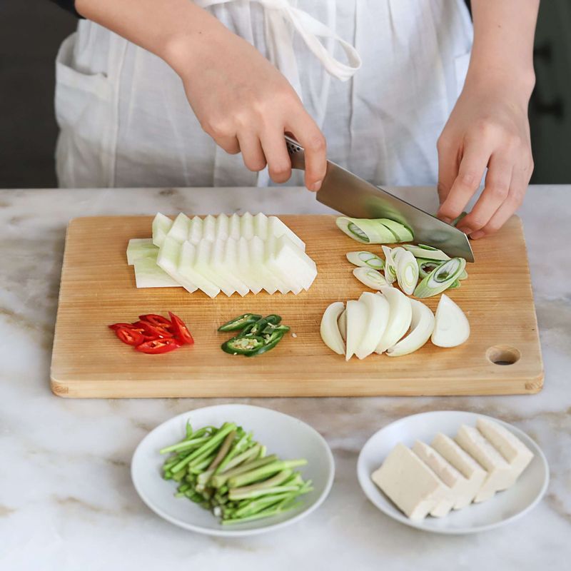 무는 납작하게 나박썰기하고, 양파는 채썰고, 미나리는 5센치 길이로 썰어주세요. 대파와 청양고추, 홍고추는 어슷썰어주세요. 두부는 한입크기로 썰어주세요.