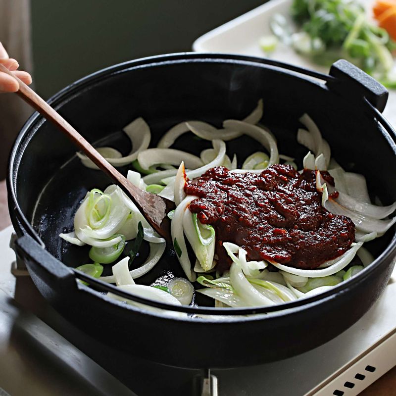 달군팬에 오일을 살짝 두르고 채썬 양파와 대파를 넣어 볶아주세요. 대파의 향이 올라오면 양념재료를 넣어 볶고, 주꾸미, 당근, 청양고추, 홍고추를 넣어 고루 섞이도록 빠르게 볶아주세요. 마지막에 참기름과 통깨를 뿌려주세요.