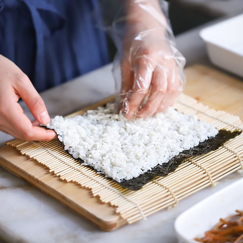 김발에 김을 올리고 밥을 고르고 얇게 편 후, 준비한 오이, 당근, 우엉, 맛살, 단무지, 달걀을 올린 후 그 위에 깻잎 2장과 묵은지, 참치를 올려 김밥을 말아주세요.
