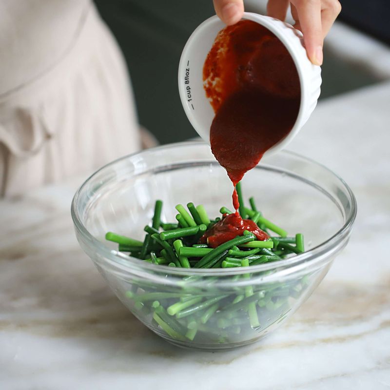 데친 마늘종을 양념에 넣고 무친 후, 통깨를 뿌려주세요.