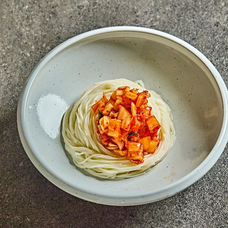 그릇에 삶은 국수를 담고, 김치, 오이, 청홍고추, 삶은달걀을 올린 후 살얼음이 생긴 육수를 붓고 통깨를 뿌려 마무리 해주세요.