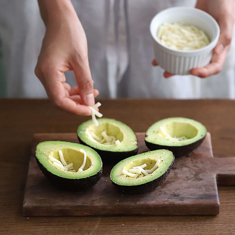 아보카도에 피자치즈를 1큰술씩 넣은 후 달걀과 베이컨을 넣어주세요.