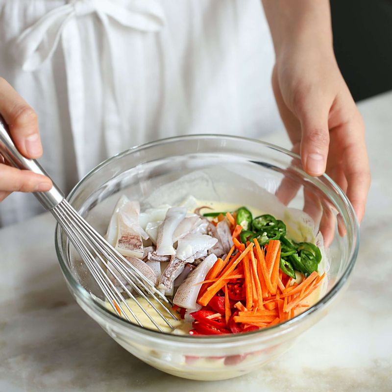 반죽 양념에 썰어 둔 당근, 청홍고추, 오징어를 넣어 섞어주세요. 마지막에 부추를 넣어 가볍게 섞어주세요.