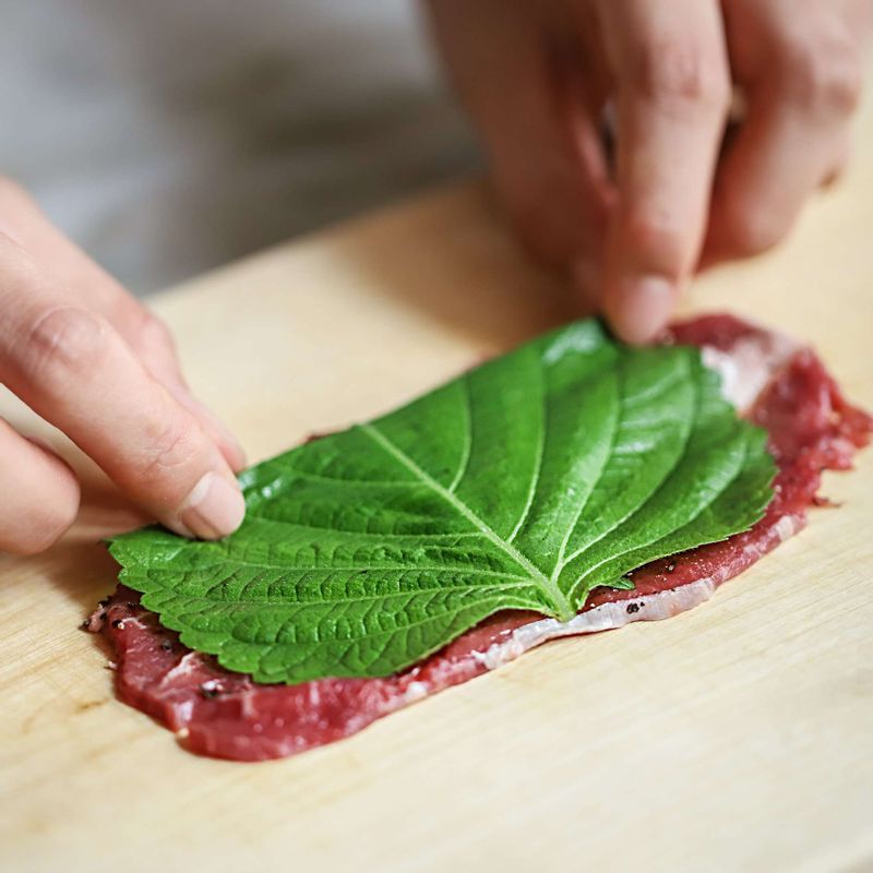 밑간 한 쇠고기에 깻잎을 깔고 팽이버섯과 쪽파를 올려 돌돌 말아주세요.
(Tip. 쇠고기 양쪽 끝에 전분가루를 살짝 묻히면 말았을 때 풀리지 않아요.)