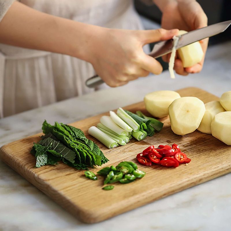 감자는 껍질을 벗기고 반으로 자르고 모서리를 다듬어주세요. 대파는 반으로 갈라 6센치 길이로 자르고, 고추는 어슷하게 썰어주세요. 깻잎은 굵게 채를 썰어주세요.