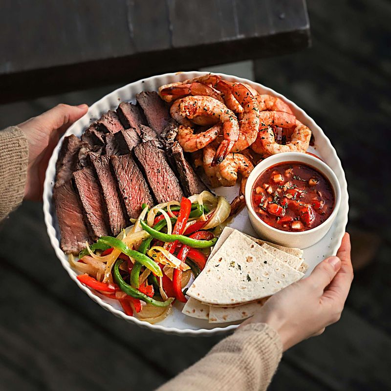 토르티야에 구운 쇠고기와 새우, 야채, 살사소스를 올리고 가장자리를 접어 돌돌 말아주세요. (기호에 따라 사워크림 구아카몰소스, 잘게 채 썬 치즈 등을 함께 드셔도 맛있답니다.)