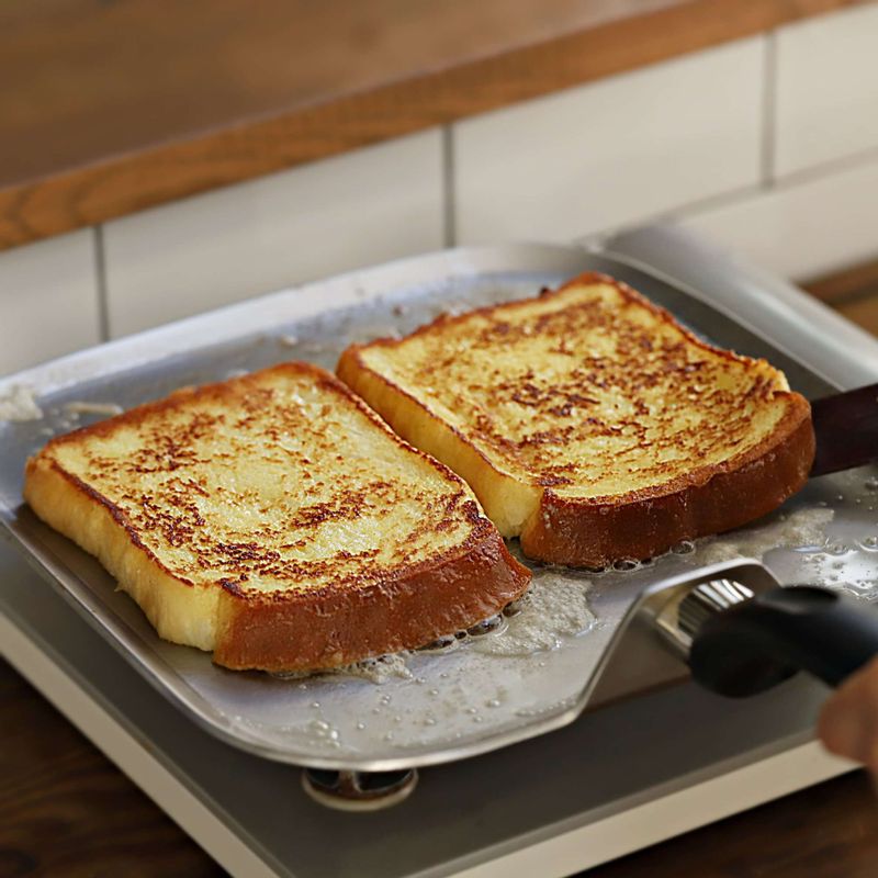 달군 팬에 버터를 두르고 빵을 올려 약불에서 3~5분간 익혀주세요. 빵 위에 설탕을 뿌리고, 뒤집어서 진한 갈색이 날 때까지 익혀주세요.