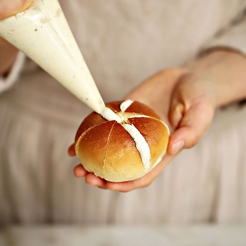 비닐팩에 필라델피아 크림치즈 갈릭을 넣고 약간의 구멍을 내어 칼집을 낸 모닝빵 사이사이에 넣어주세요.