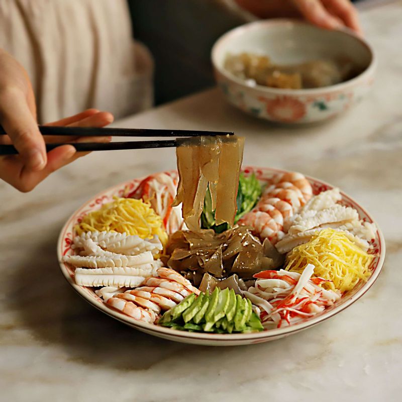 접시에 달걀지단, 크래미, 오이, 오징어, 새우를 돌려 담고 가운데 양념한 양장피를 올려주세요.