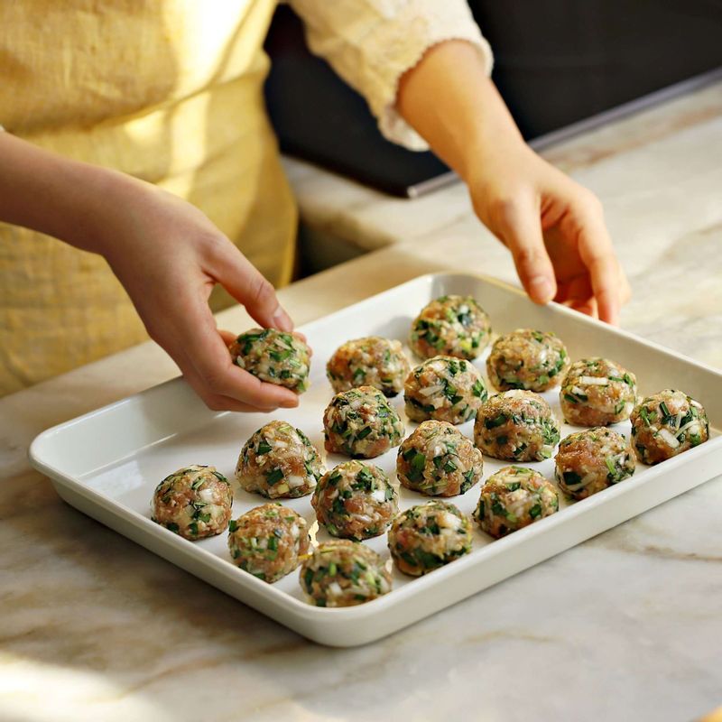 만두소를 한입에 먹기좋게 30g정도로 떼어 동그랗게 빚은 후 접시에 전분가루와 밀가루를 섞어 만두소를 굴려가며 표면에 가루를 묻혀주세요.