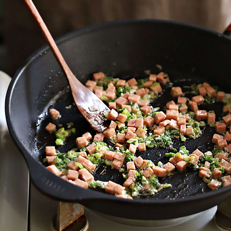 달군 팬에 기름을 두르고 대파를 1분 정도 볶다가 스팸을 넣어 볶아주세요.
