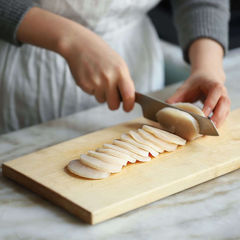 관자살을 소금물에 흔들어 씻은 후 물기를 제거하고 0.3센치 두께로 썰어주세요. (관자의 날개부분과 꼭지부분은 소금물에 흔들어 씻은 후 적당한 크기로 잘라 찌개와 국에 이용하시면 좋답니다.)