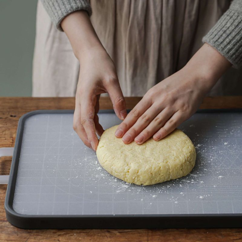3cm 정도 두께로 둥글고 납작하게 만든 후 도마에 덧가루를 뿌려 얹어주세요. 스크래퍼에 밀가루를 묻힌 후 반죽을 6등분으로 잘라주세요.