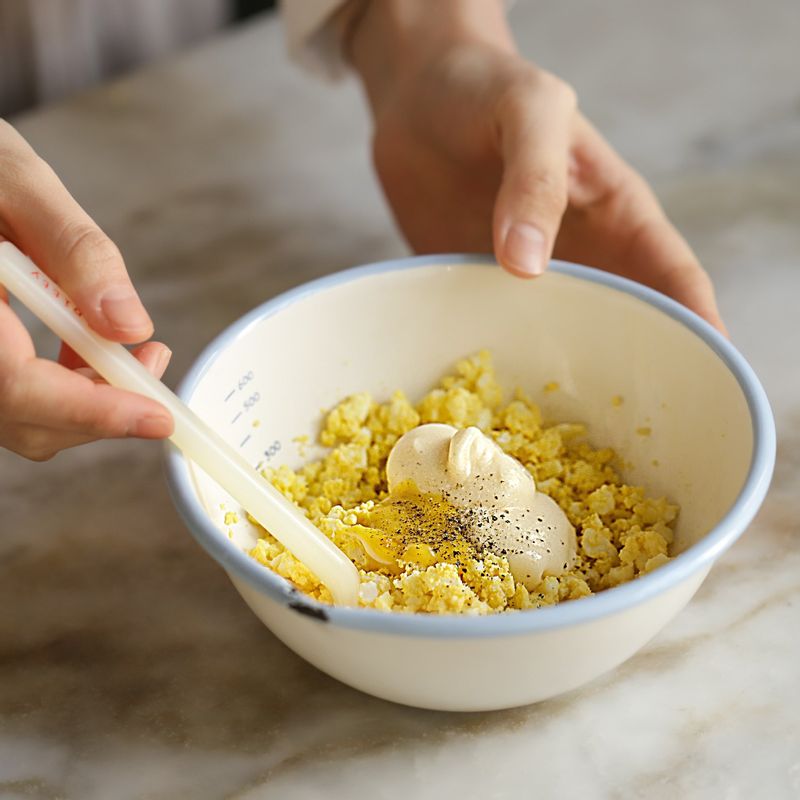 삶은 달걀은 찬물 또는 얼음물에 넣어 식힌 후 껍질을 까주세요. 볼에 완숙 달걀을 넣은 후 포크로 으깨주세요. 달걀 양념 재료를 넣어 섞어주세요.