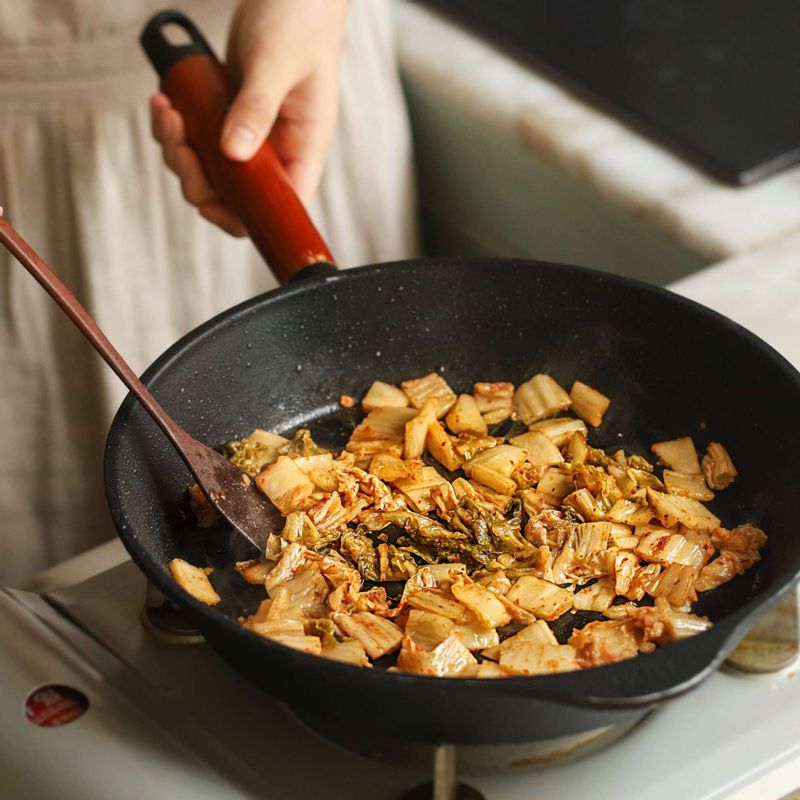 달군 팬에 기름을 넣고 김치를 넣어 중약불에서 볶다가 양념한 돼지고기와 양파를 넣어 볶아주세요.