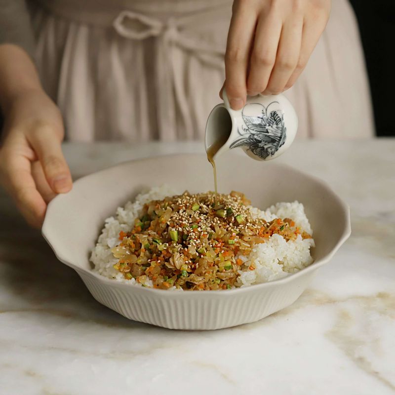 따뜻한 밥에 볶은 야채와 참기름, 깨를 넣고 골고루 섞은 후 한 입 크기로 동그랗게 모양을 잡아 주먹밥을 만들고 쇠고기를 올려 감싸주세요.