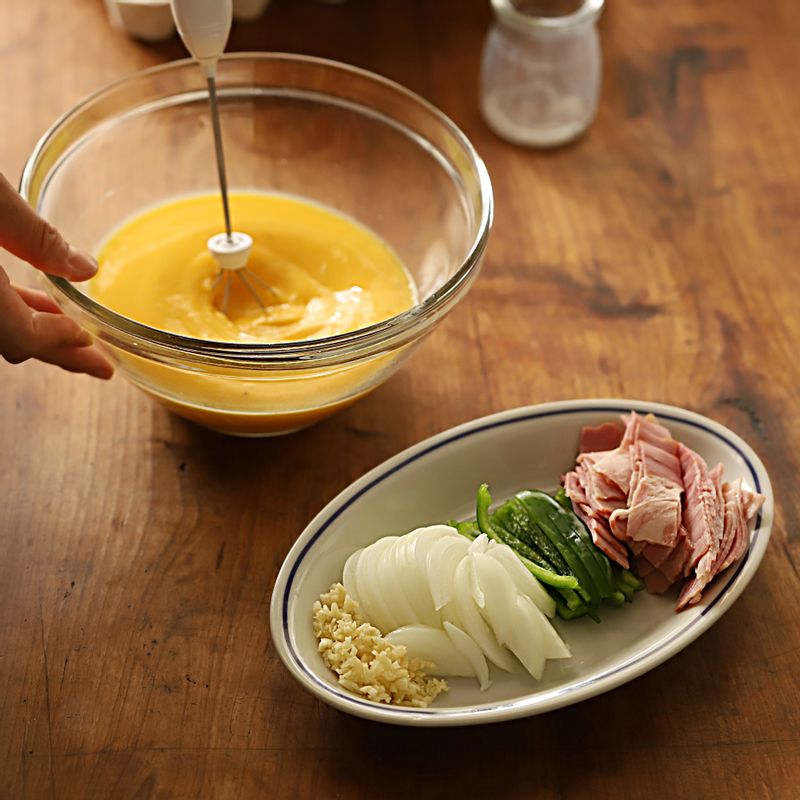 마늘은 잘게 다지고, 양파와 청피망은 얇게 채썰어주세요. 베이컨은 1cm간격으로 자르고, 볼에 달걀물 재료를 넣어 섞어주세요.