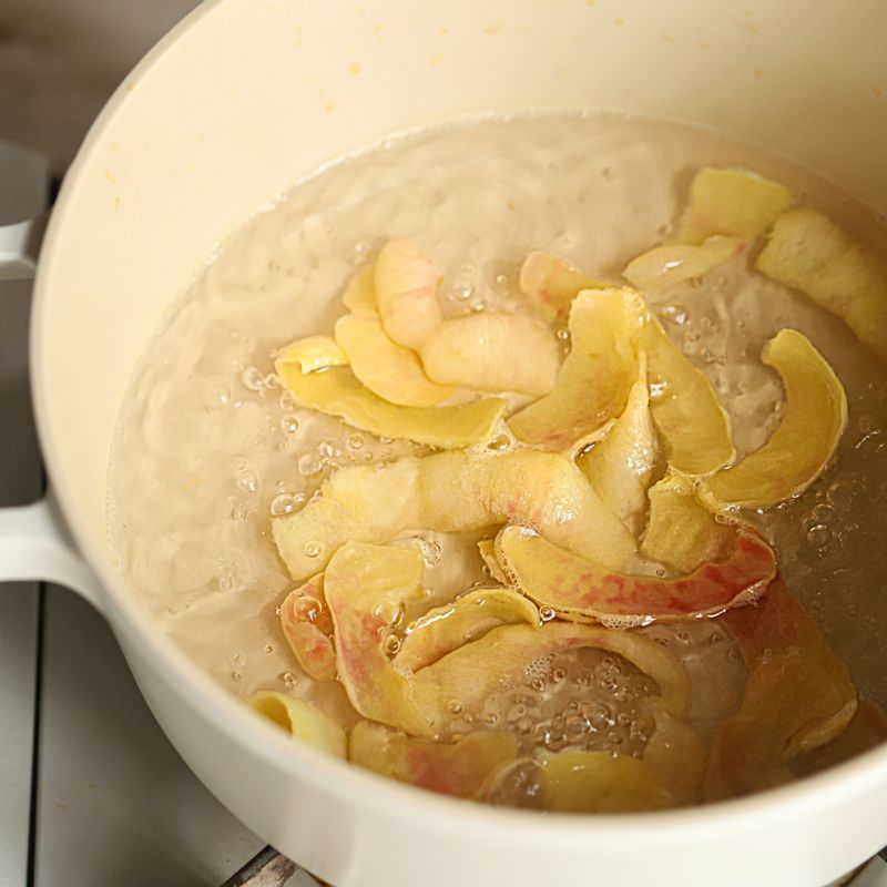 냄비에 물과 복숭아의 껍질을 넣고 복숭아의 붉은 색 물이 나올 때까지 끓여준 후 껍질을 건지고 설탕을 넣어 끓여주세요.