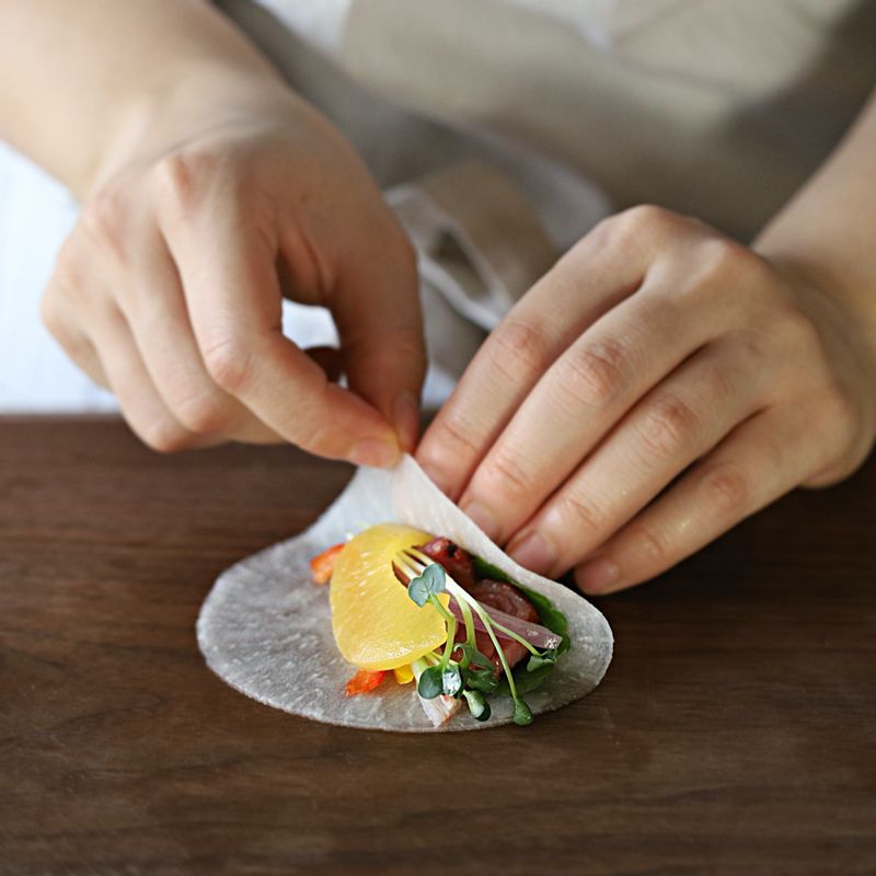 물기를 살짝 제거한 쌈무에 반으로 자른 깻잎을 올리고 크래미, 채썬 야채, 황도, 무순, 알파파, 훈제오리 적당량 올린 후 부채꼴 모양으로 말아주세요.