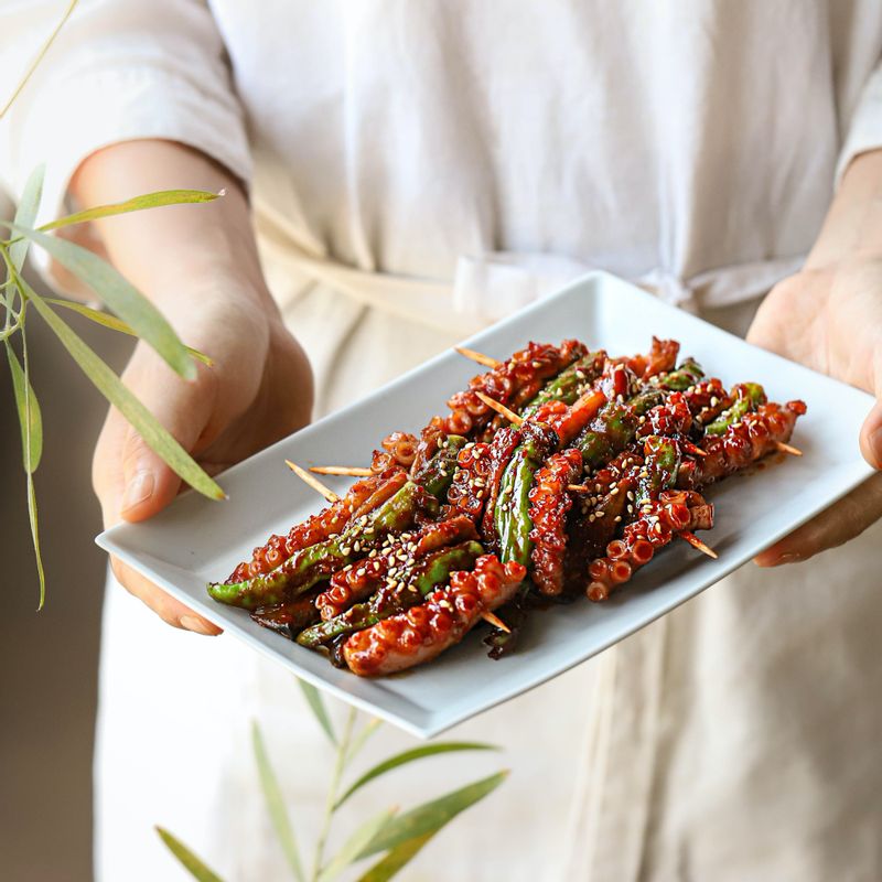 뾰죡한 꼬치 양쪽 끝을 자른 후 접시에 낙지 꼬치구이를 담고 통깨를 뿌려주세요.