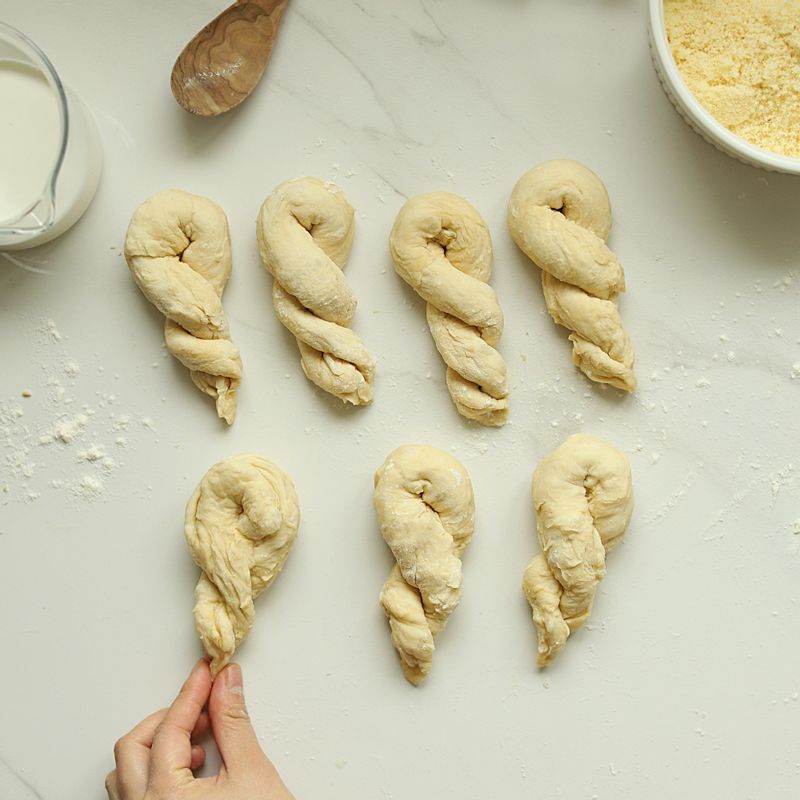 작업대에 밀가루를 소량 뿌린 후 해동된 크로와상 반죽을 손으로 길게 밀어 꽈배기 모양으로 꼬아 주세요.