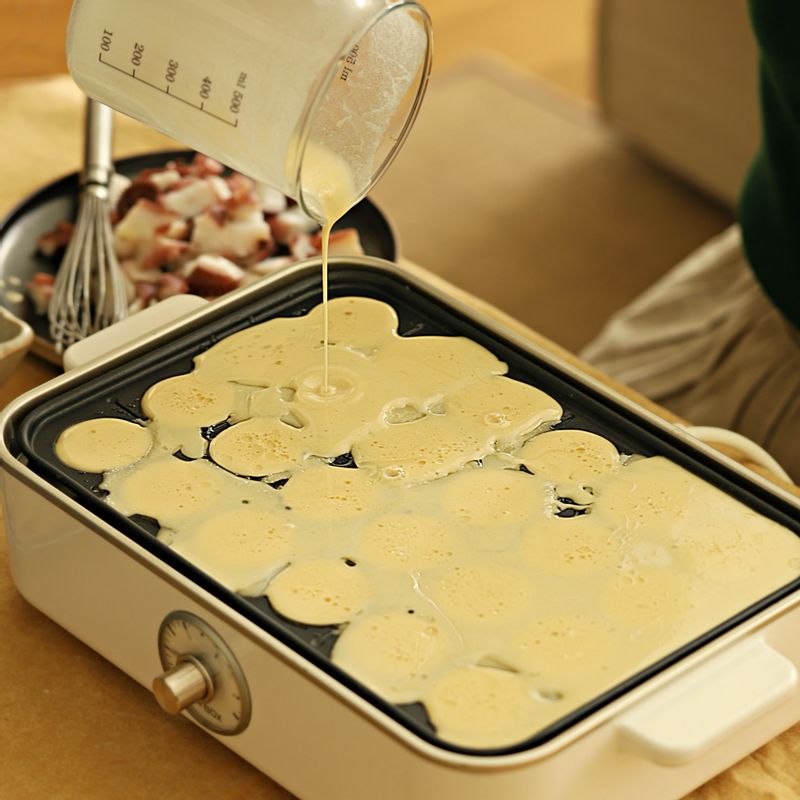 타코야끼 틀에 열이 올라오면 기름을 칠하고 반죽을 부어주세요. 문어와 쪽파를 넣고 익혀주세요.