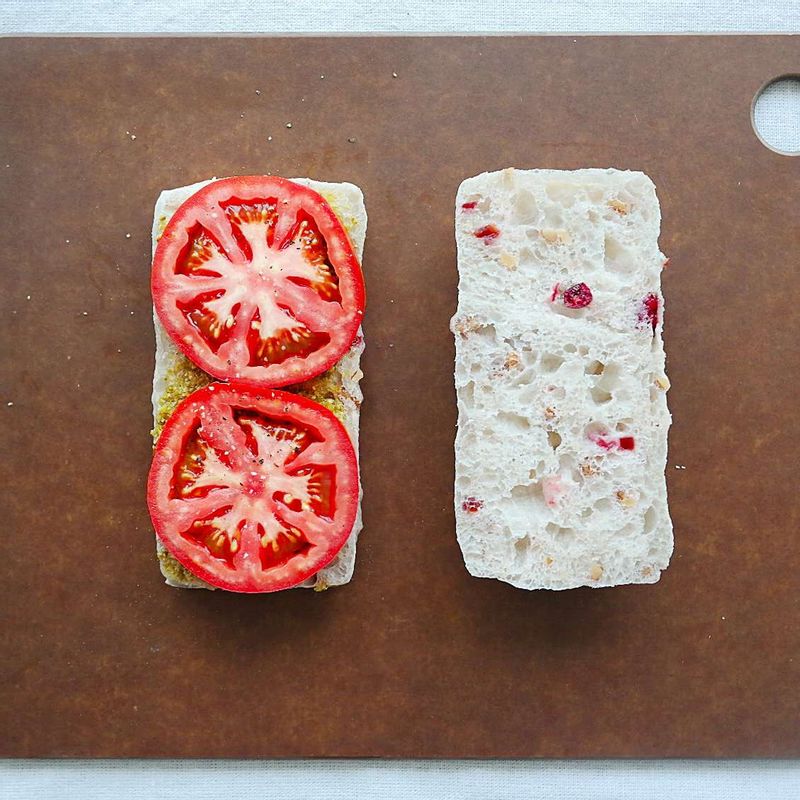 치아바타를 반으로 갈라 한쪽 면에 바질페스토를 바른 후 토마토 슬라이스를 올려주세요.